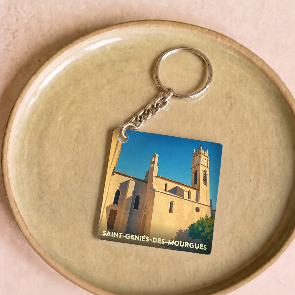 Porte-clés souvenir de la ville de Saint-Geniès-des-Mourgues avec une illustration stylisée de son église.