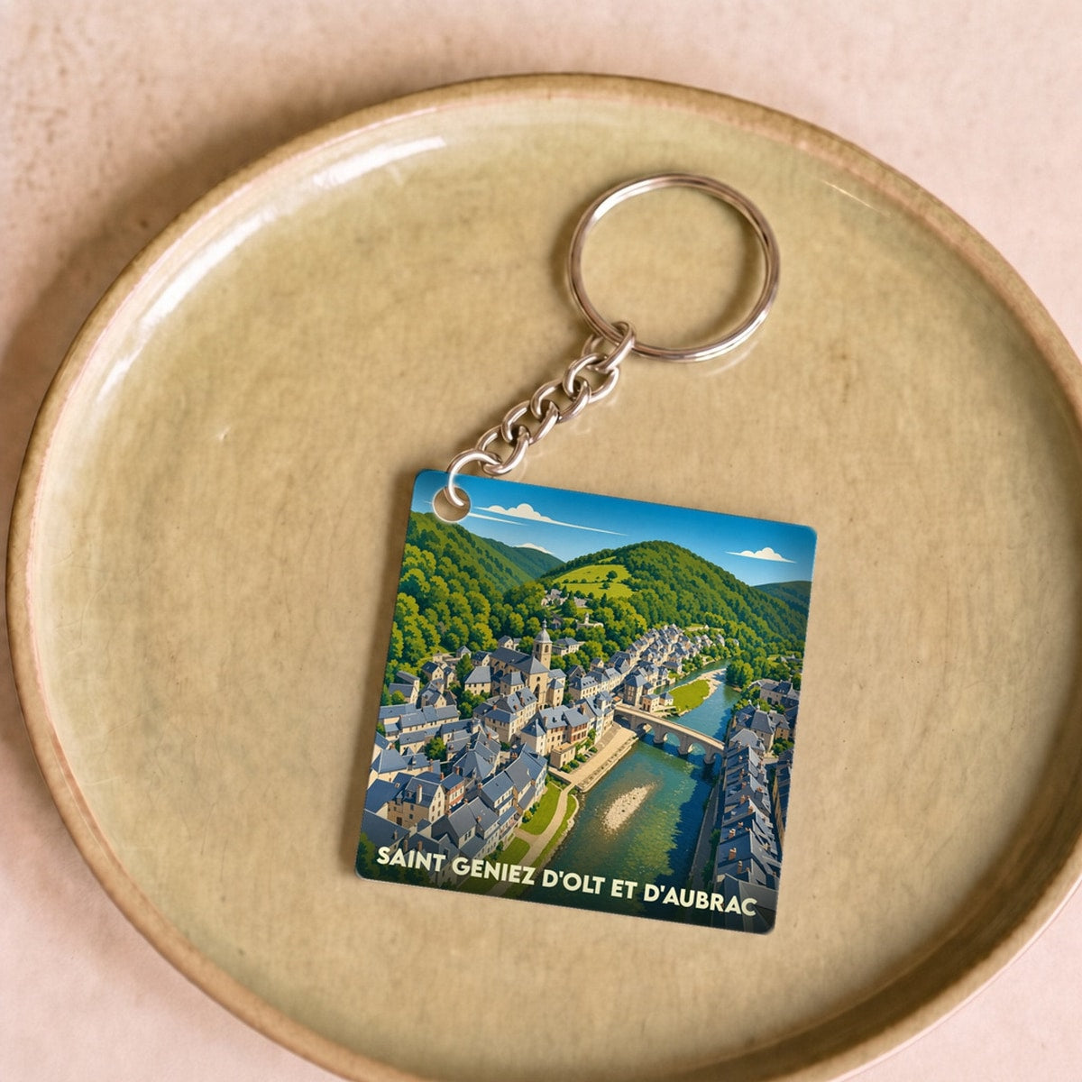 Porte-clés souvenir de Saint Geniez d'Olt et d'Aubrac avec une illustration stylisée.