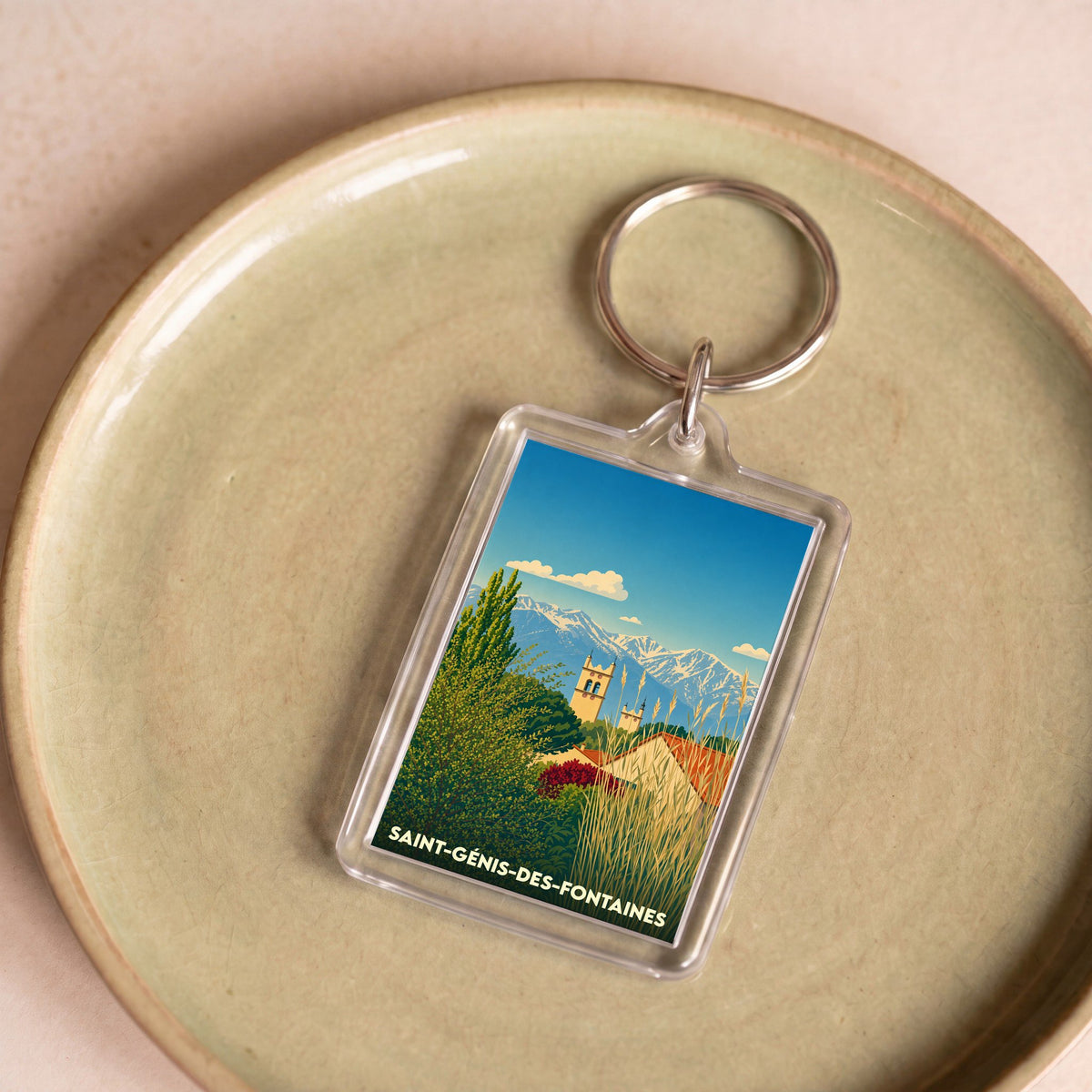 Porte-clés souvenir de la ville de Saint-Génis-des-Fontaines avec une illustration stylisée.