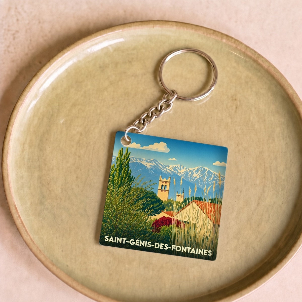 Porte-clés souvenir de la ville de Saint-Génis-des-Fontaines avec une illustration stylisée.