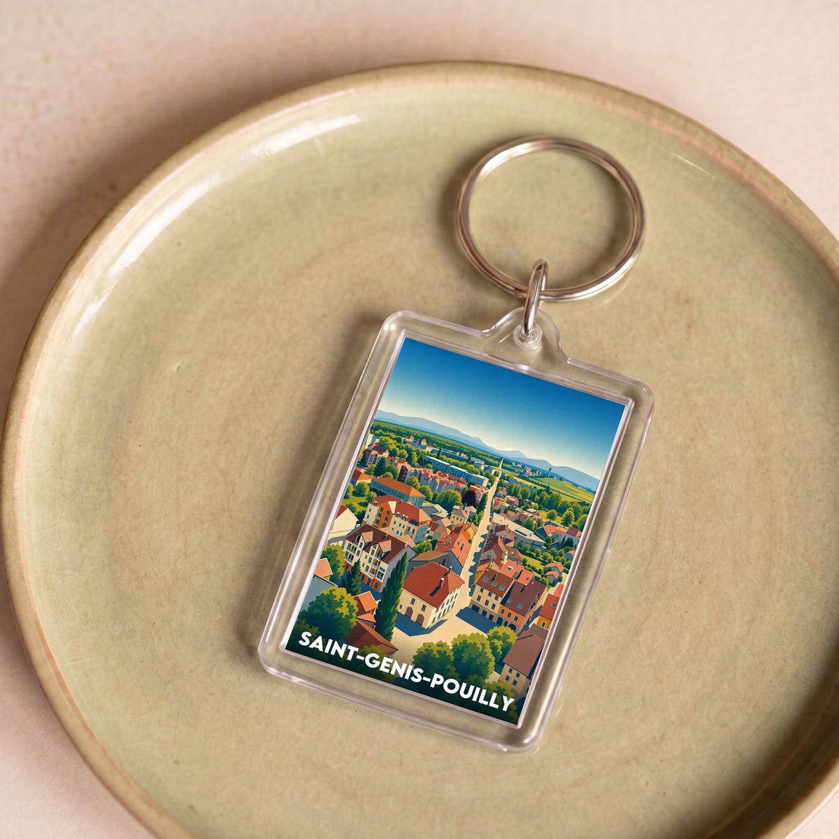 Porte-clés souvenir de la ville de Saint-Genis-Pouilly avec une illustration stylisée d'une vue aérienne.