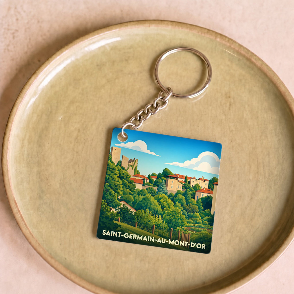 Porte-clés souvenir de Saint-Germain-au-Mont-d'Or avec une illustration stylisée du village et ses collines.
