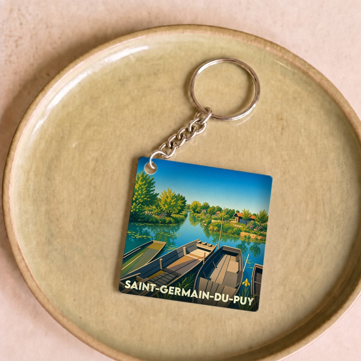 Porte-clés souvenir de la ville de Saint-Germain-du-Puy avec une illustration stylisée de barques sur l'eau.