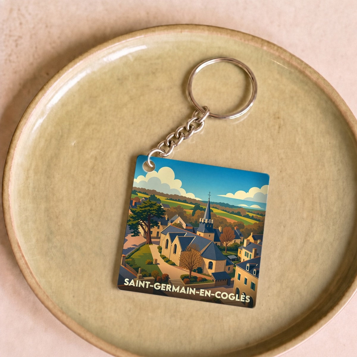 Porte-clés souvenir de Saint-Germain-en-Coglès avec une illustration stylisée du village.