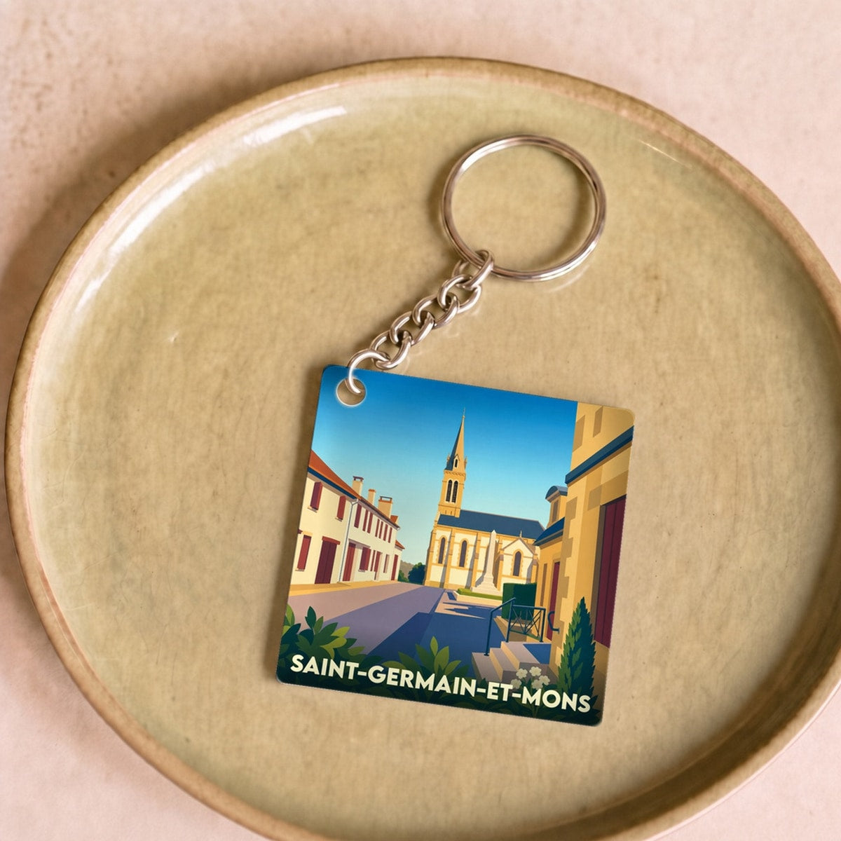 Porte-clés souvenir de la ville de Saint-Germain-et-Mons avec une illustration stylisée.
