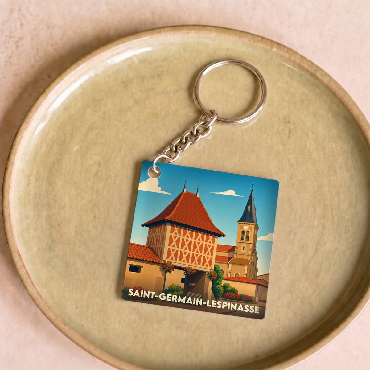 Porte-clés souvenir de la ville de Saint-Germain-Lespinasse avec une illustration stylisée de son patrimoine.