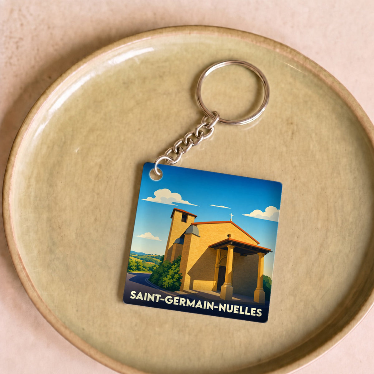Porte-clés souvenir de la ville de Saint-Germain-Nuelles avec une illustration stylisée de son patrimoine.