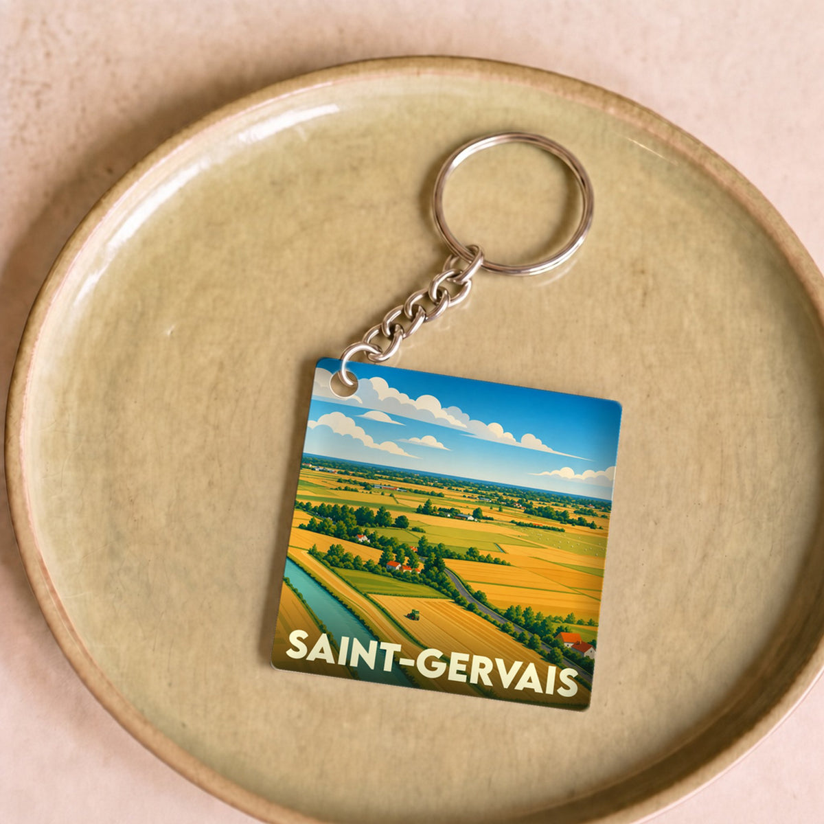 Porte-clés souvenir de la ville de Saint-Gervais avec une illustration stylisée d'un paysage rural.