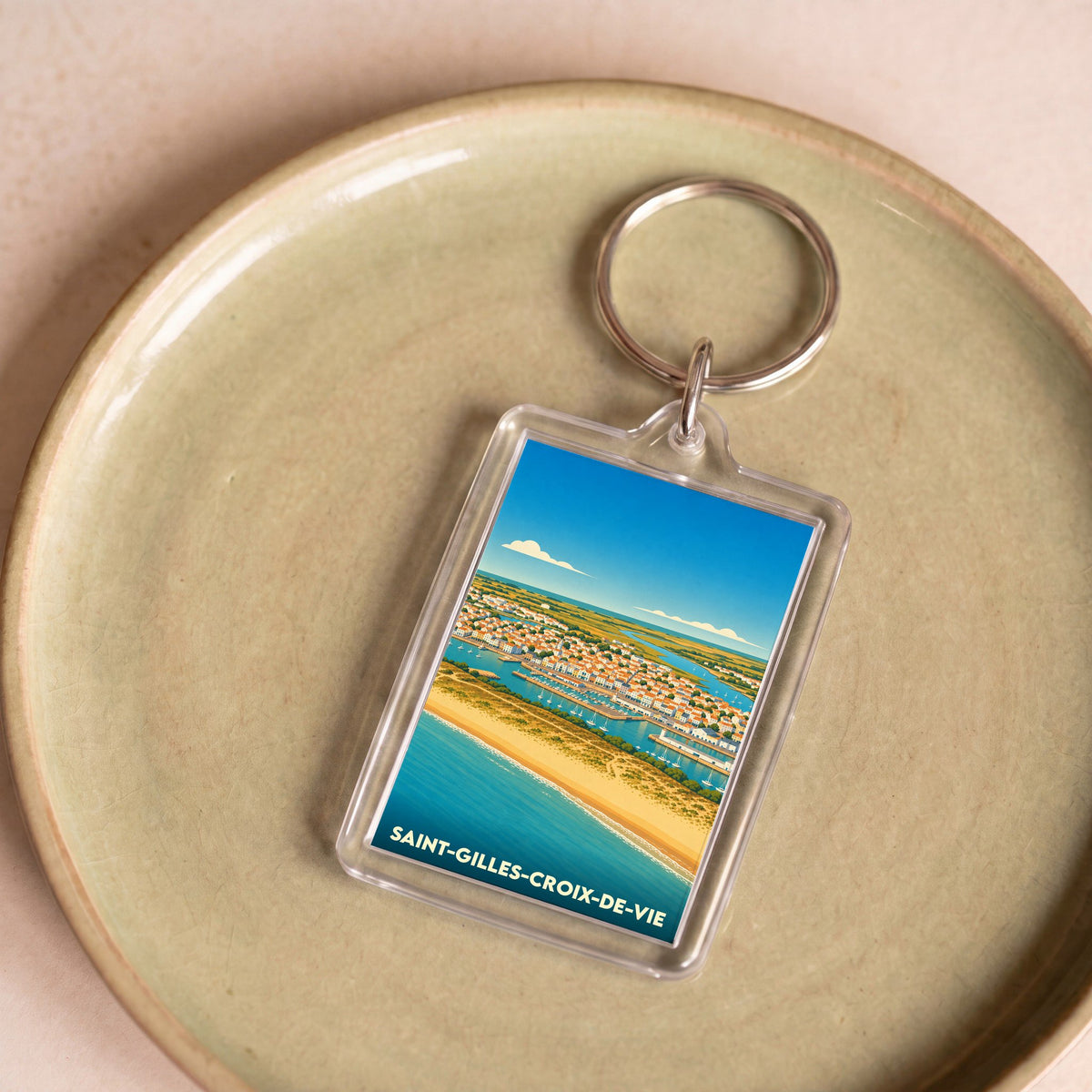 Porte-clés souvenir de la ville de Saint-Gilles-Croix-de-Vie avec une illustration stylisée du port et de la plage.