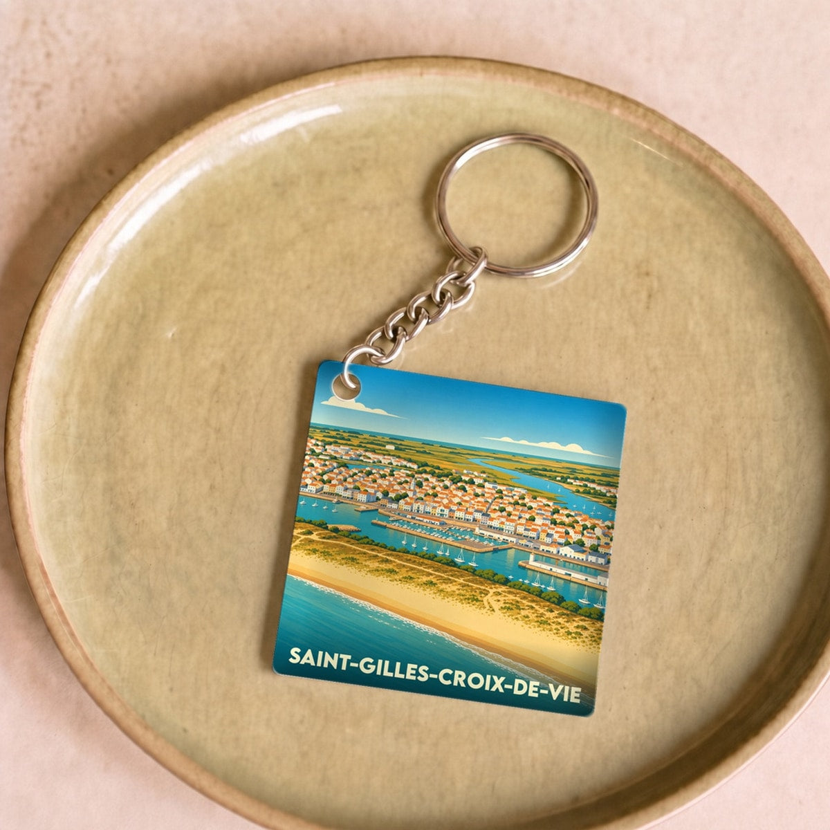 Porte-clés souvenir de la ville de Saint-Gilles-Croix-de-Vie avec une illustration stylisée du port et de la plage.