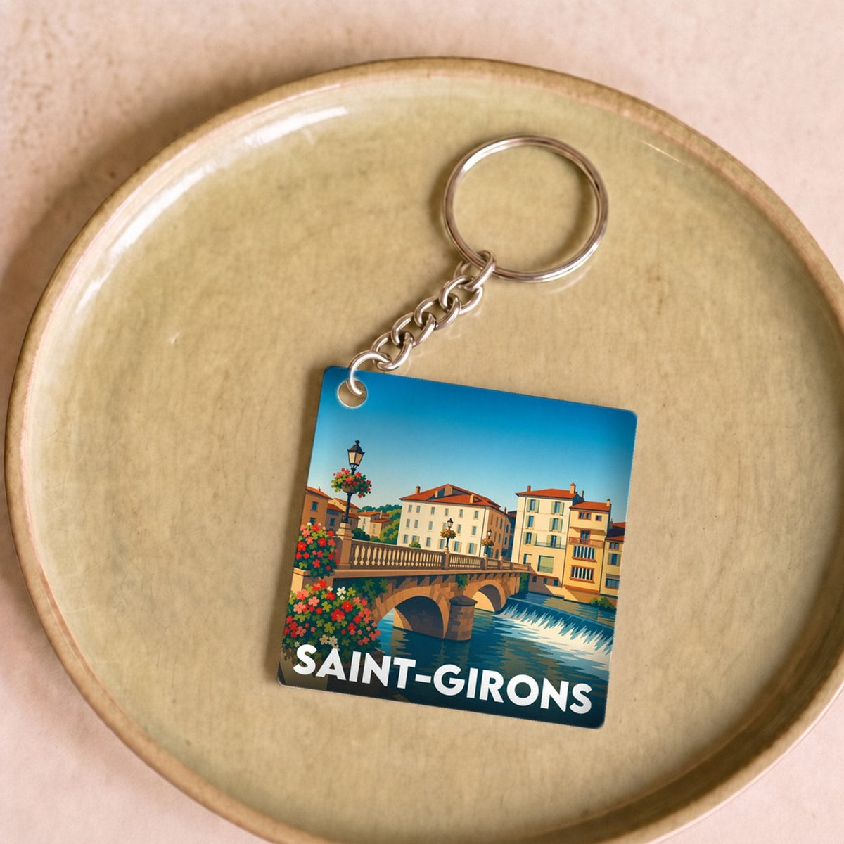 Porte-clés souvenir de la ville de Saint-Girons avec une illustration colorée.