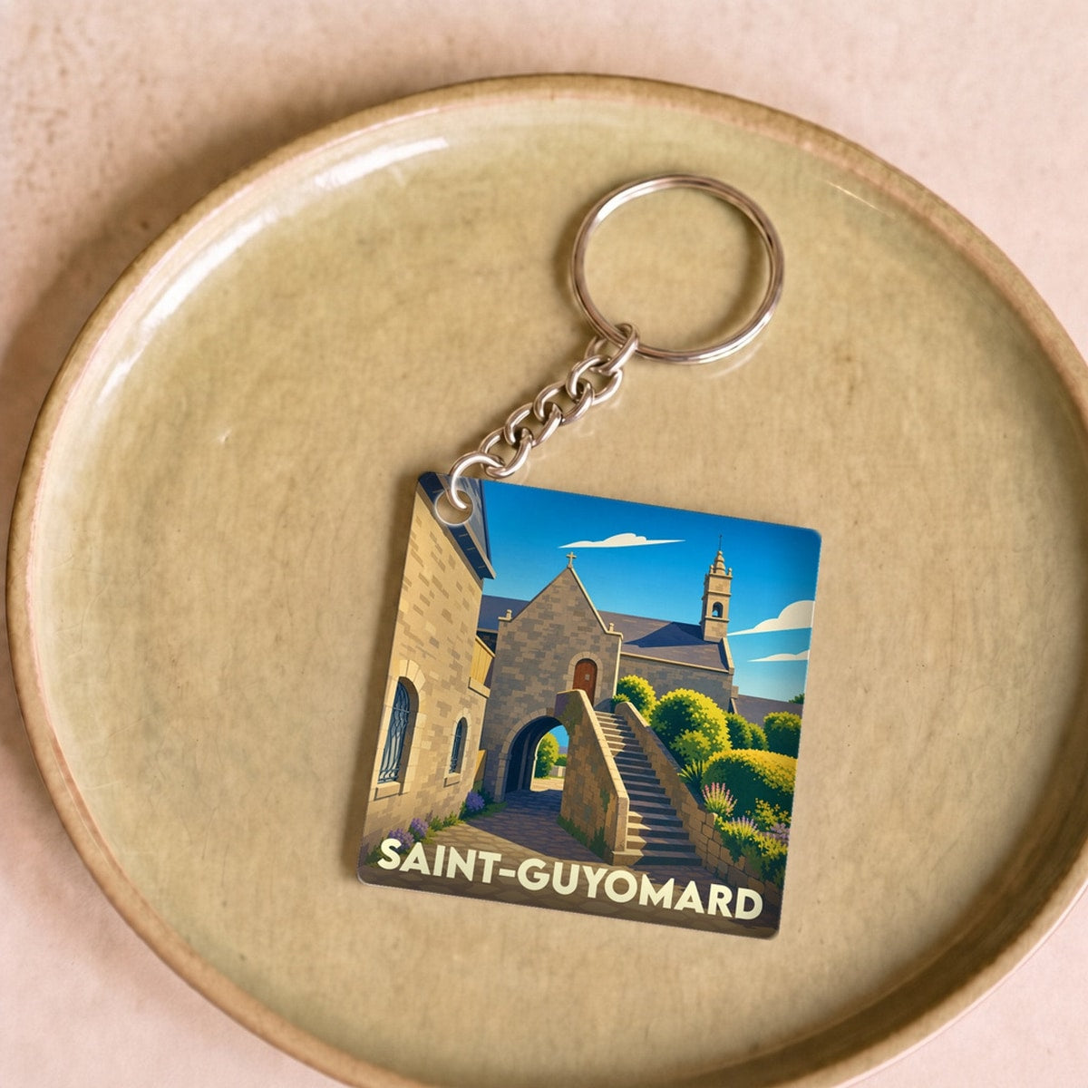 Porte-clés souvenir de la ville de Saint-Guyomard avec une illustration stylisée d'un bâtiment historique.
