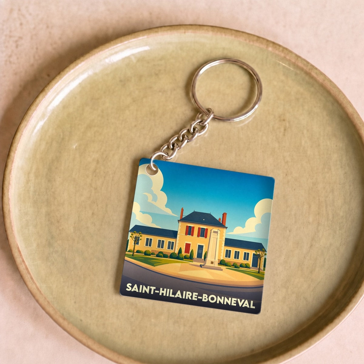 Porte-clés souvenir de la ville de Saint-Hilaire-Bonneval avec une illustration stylisée.