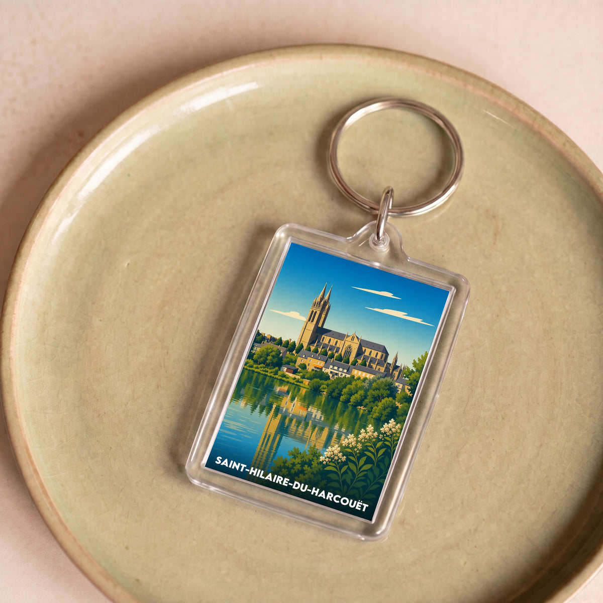 Porte-clés souvenir de la ville de Saint-Hilaire-du-Harcouët avec une illustration stylisée.