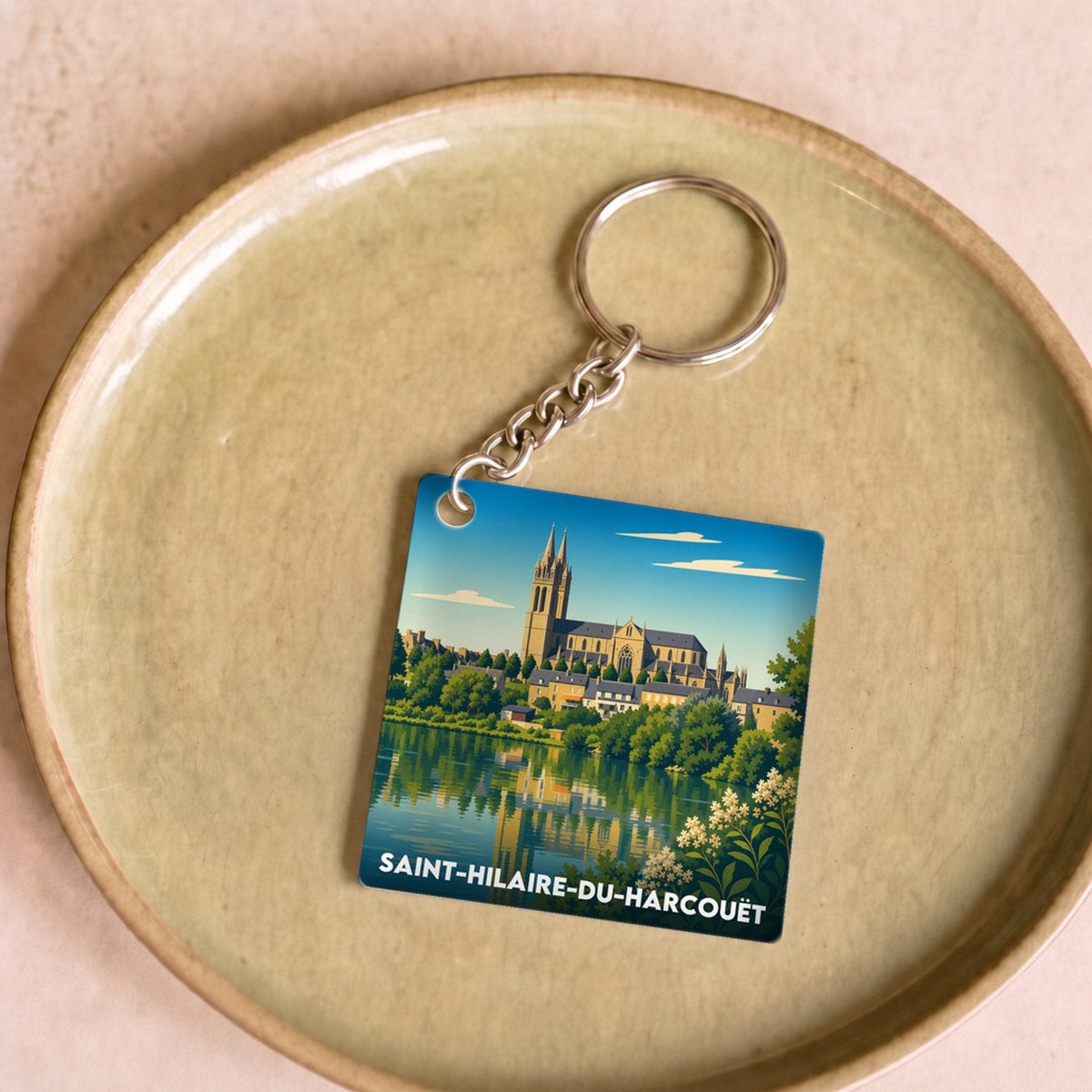 Porte-clés souvenir de la ville de Saint-Hilaire-du-Harcouët avec une illustration stylisée.