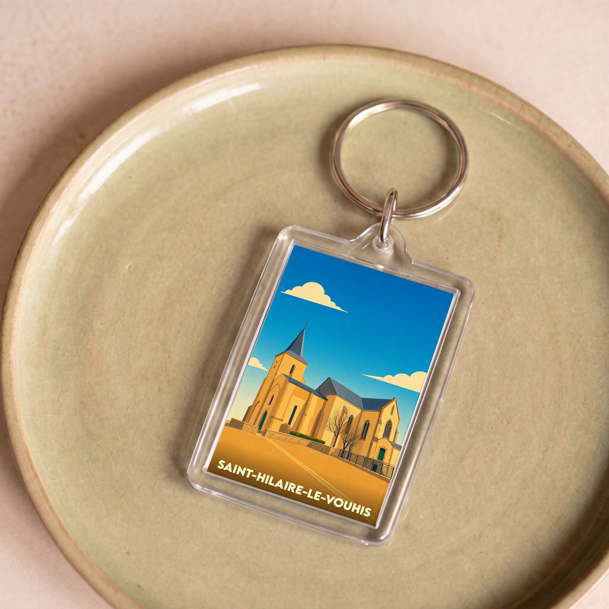 Porte-clés souvenir de la ville de Saint-Hilaire-le-Vouhis avec une illustration stylisée de son église.