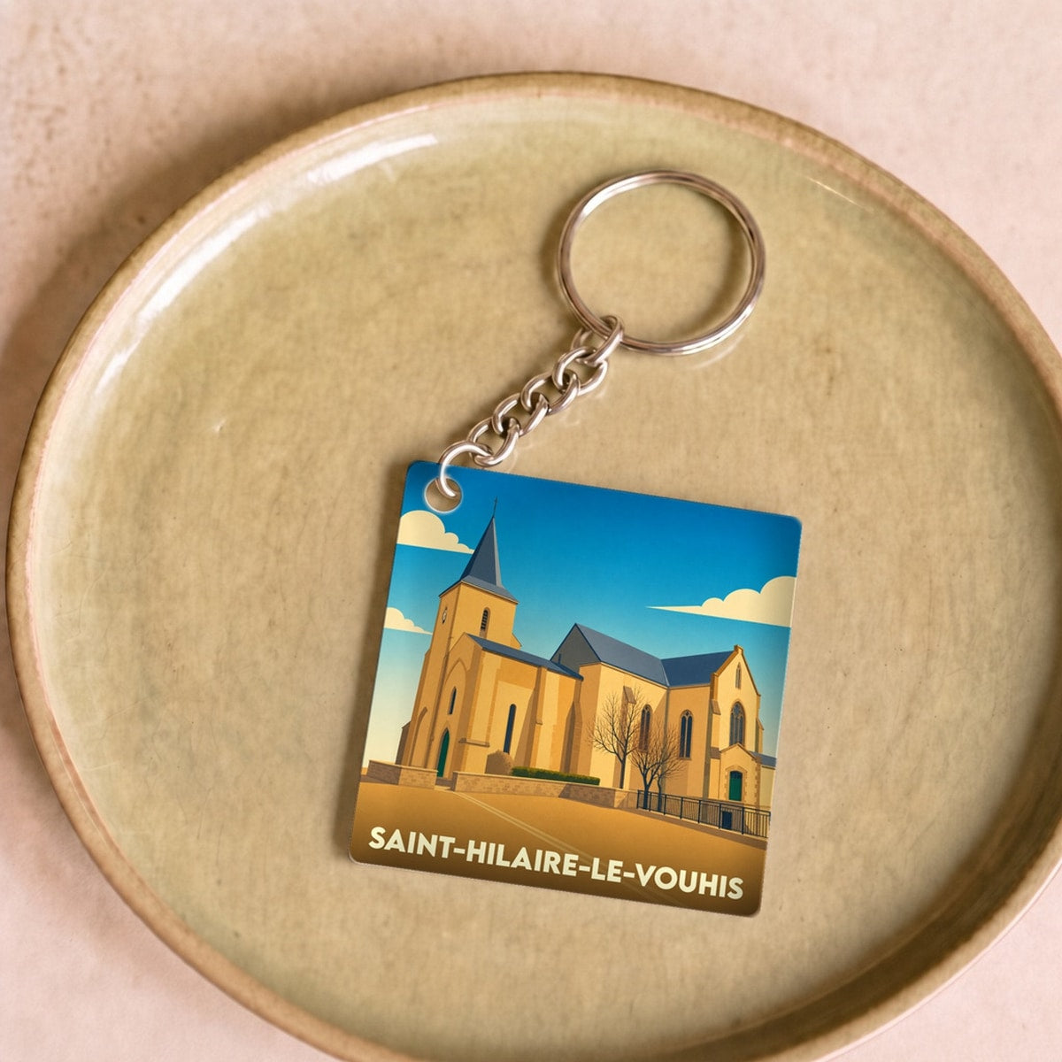 Porte-clés souvenir de la ville de Saint-Hilaire-le-Vouhis avec une illustration stylisée de son église.