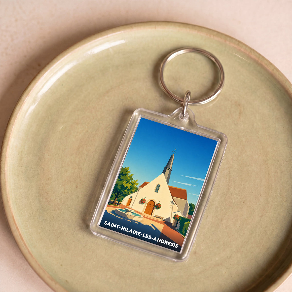 Porte-clés souvenir de Saint-Hilaire-les-Andrésis avec une illustration stylisée de son église.