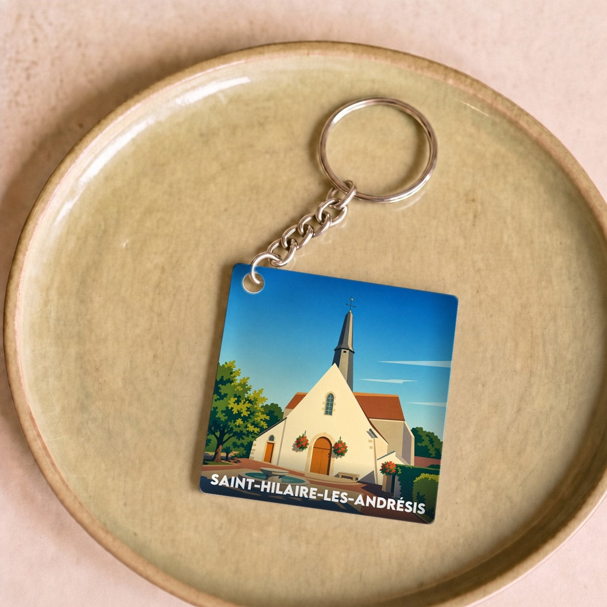 Porte-clés souvenir de Saint-Hilaire-les-Andrésis avec une illustration stylisée de son église.