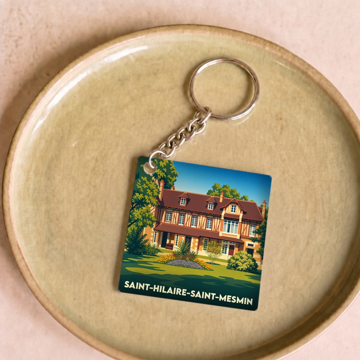 Porte-clés souvenir de la ville de Saint-Hilaire-Saint-Mesmin avec une illustration stylisée d'une maison traditionnelle.