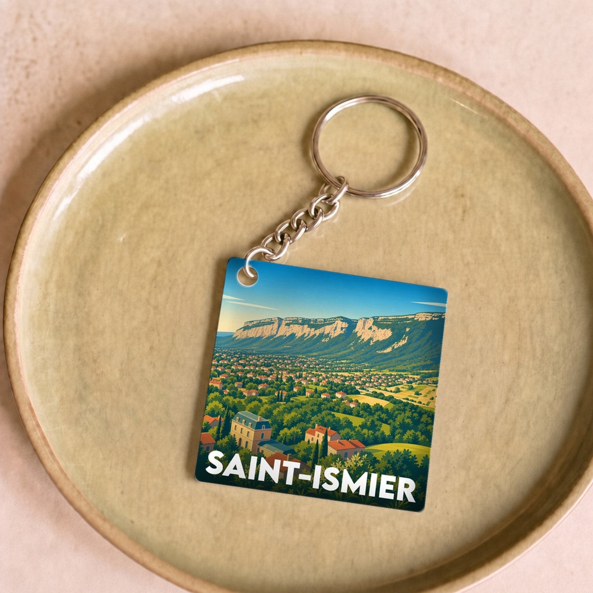 Porte-clés souvenir de la ville de Saint-Ismier avec une illustration stylisée du paysage local.