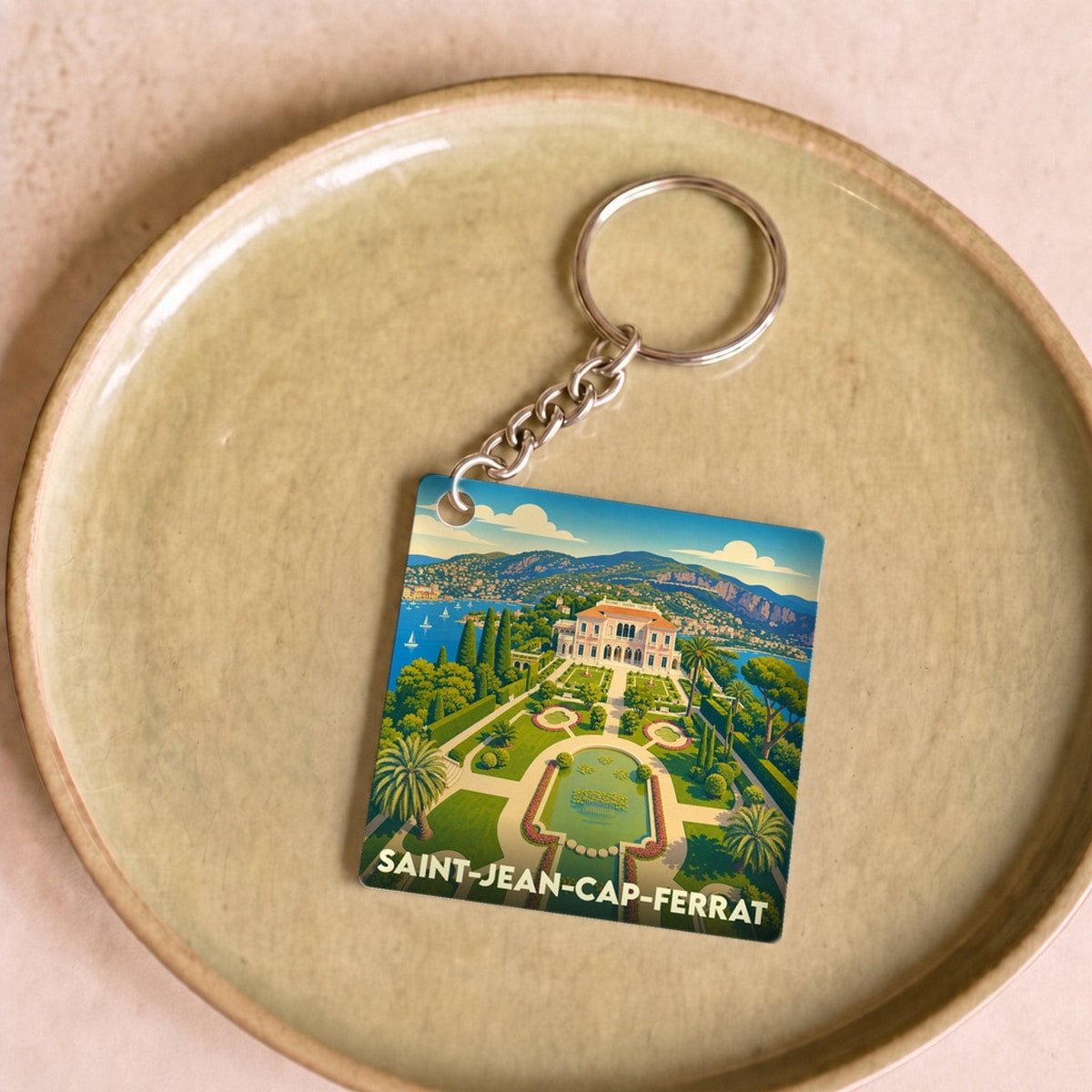 Porte-clés souvenir de la ville de Saint-Jean-Cap-Ferrat avec une illustration stylisée de la Villa Ephrussi de Rothschild.