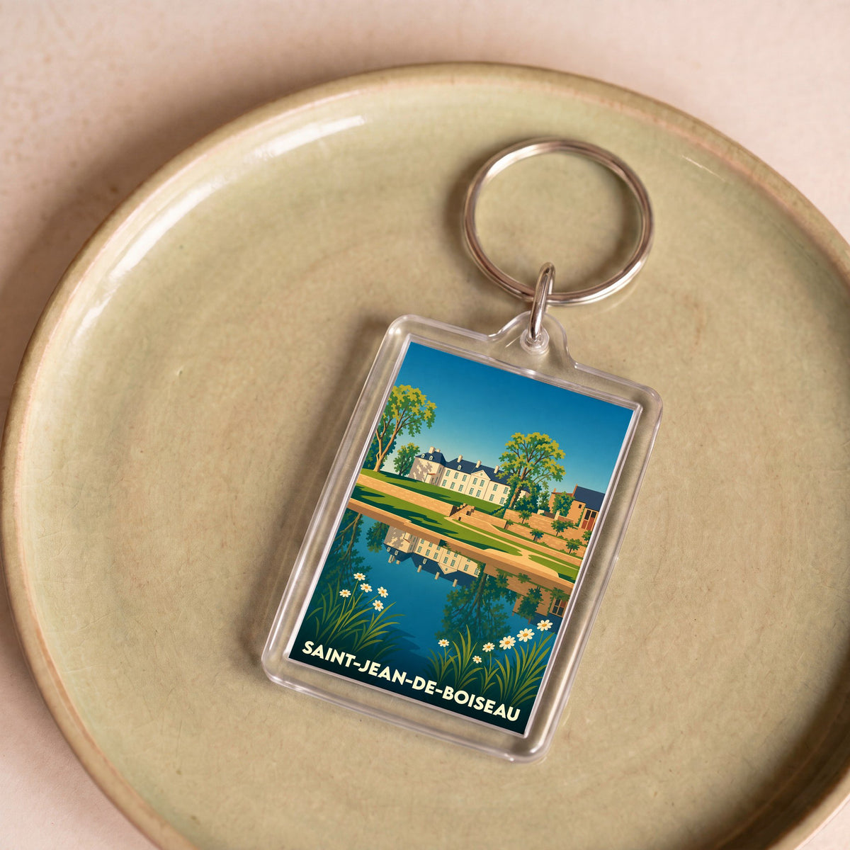 Porte-clés souvenir de la ville de Saint-Jean-de-Boiseau avec une illustration stylisée d'un château se reflétant dans l'eau.
