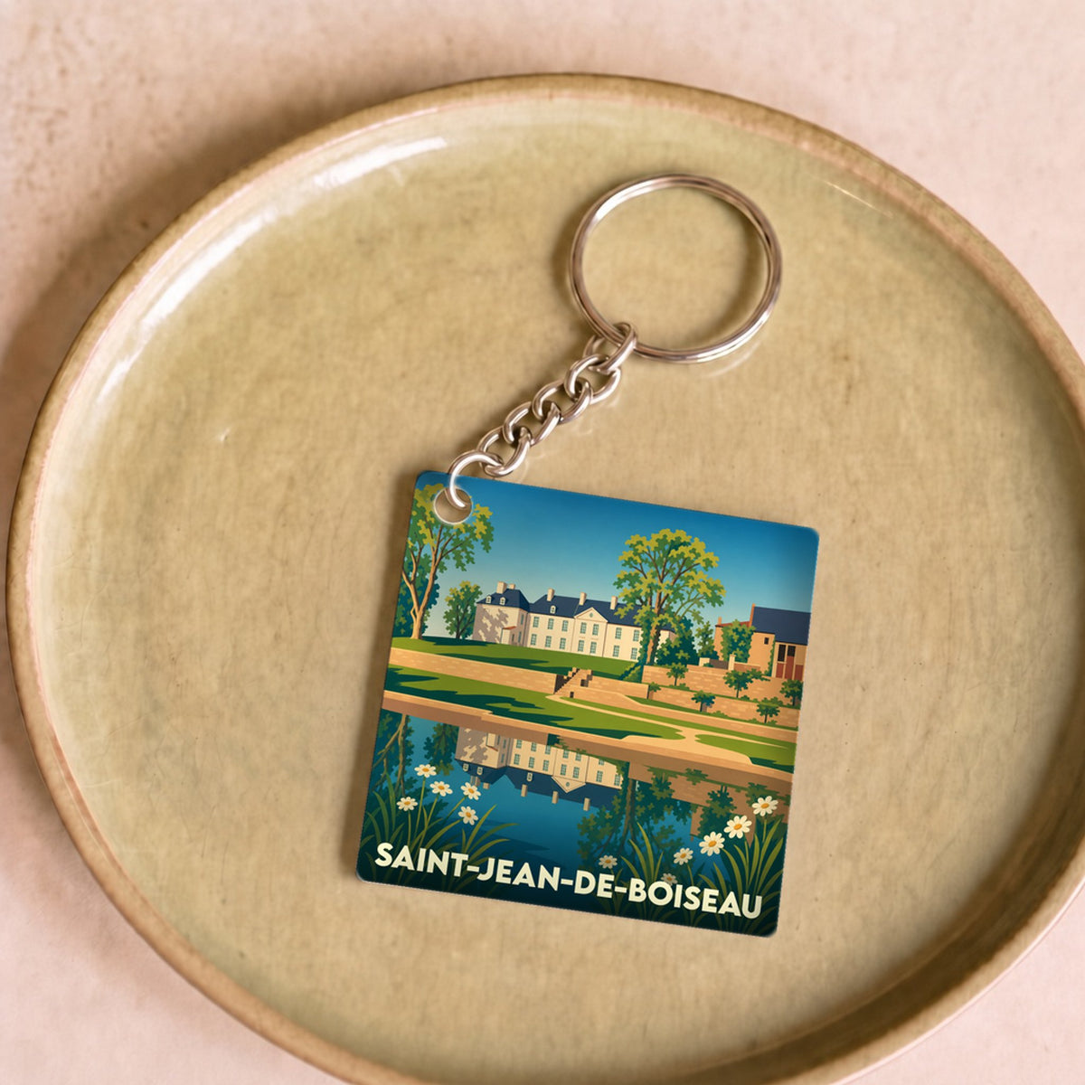 Porte-clés souvenir de la ville de Saint-Jean-de-Boiseau avec une illustration stylisée d'un château se reflétant dans l'eau.