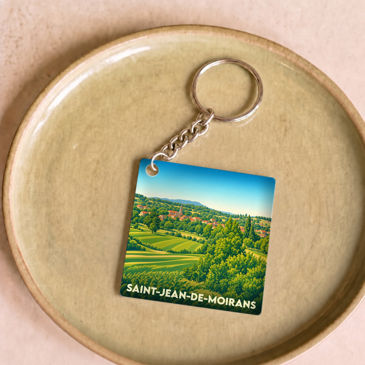 Porte-clés souvenir de la ville de Saint-Jean-de-Moirans avec une illustration stylisée de son paysage rural.
