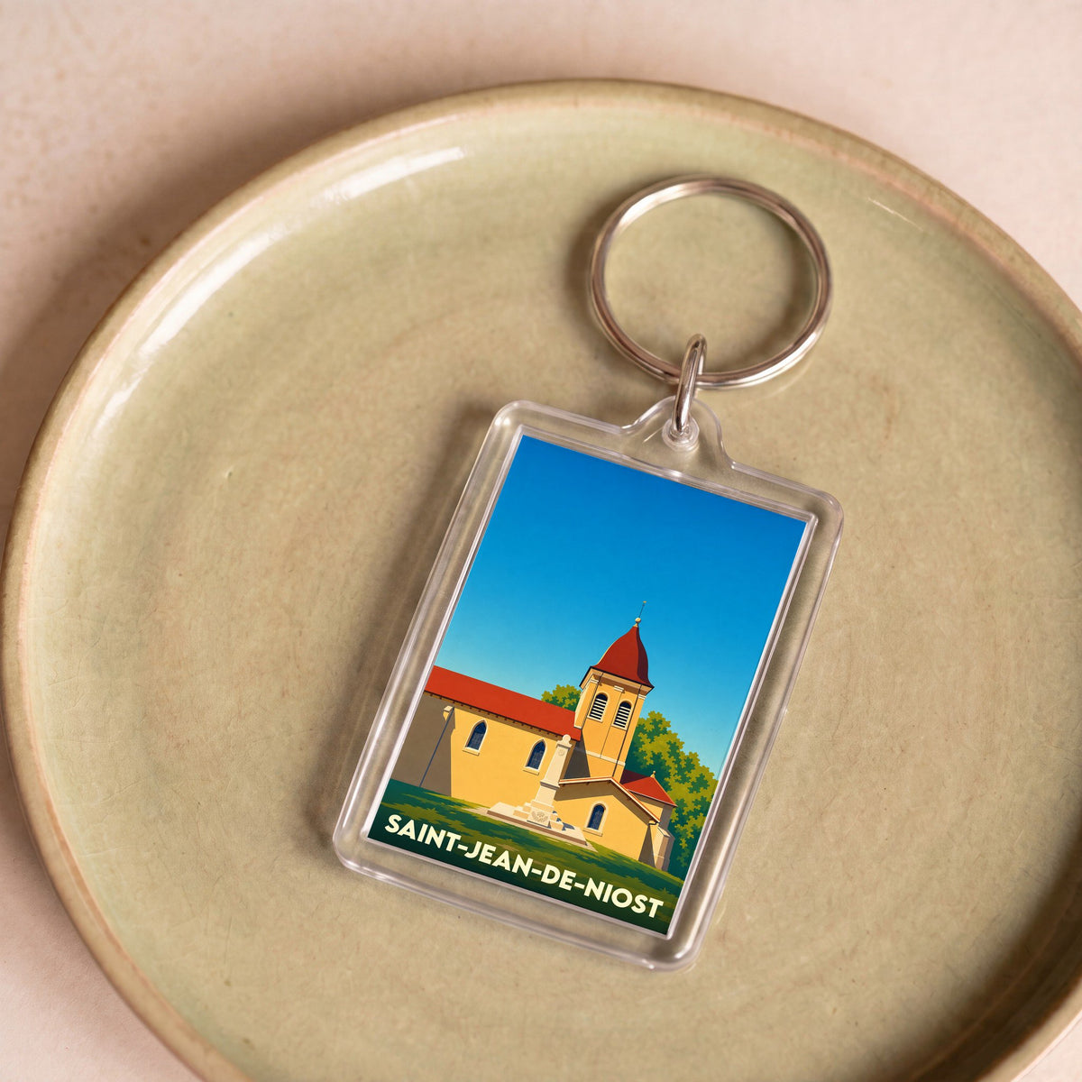 Porte-clés souvenir de la ville de Saint-Jean-de-Niost avec une illustration stylisée de son église.