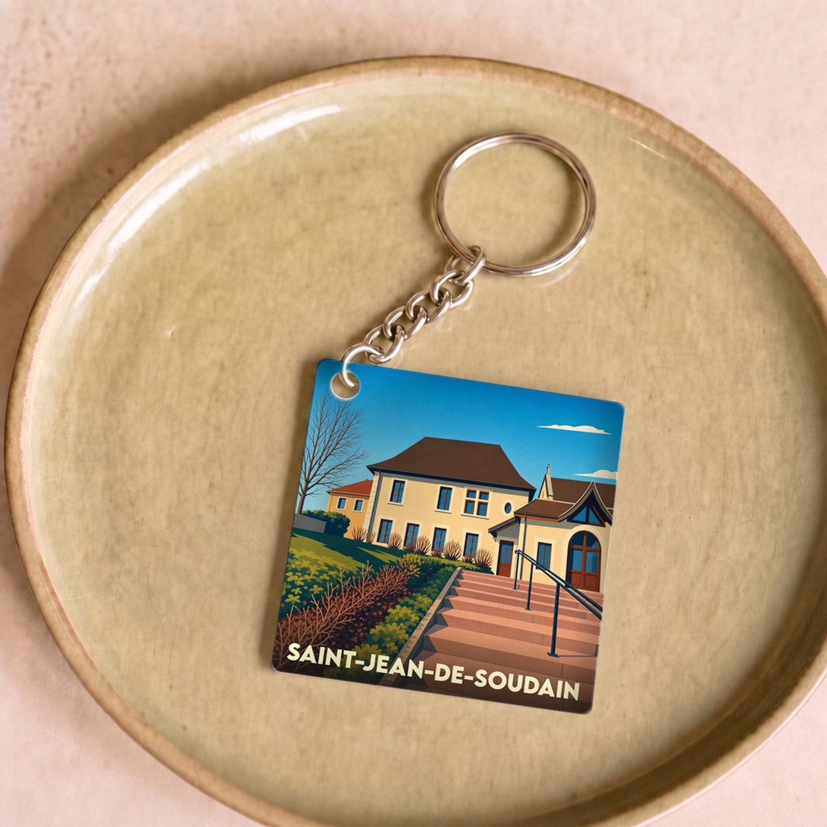Porte-clés souvenir de la ville de Saint-Jean-de-Soudain avec une illustration stylisée.