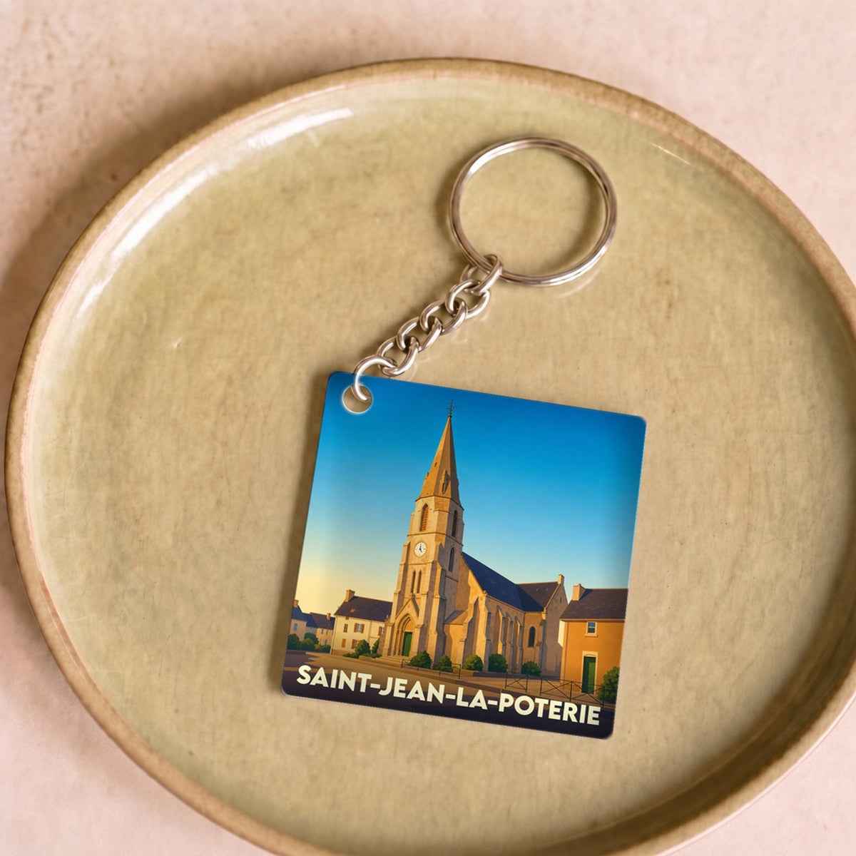 Porte-clés souvenir de la ville de Saint-Jean-la-Poterie avec une illustration stylisée de son église.