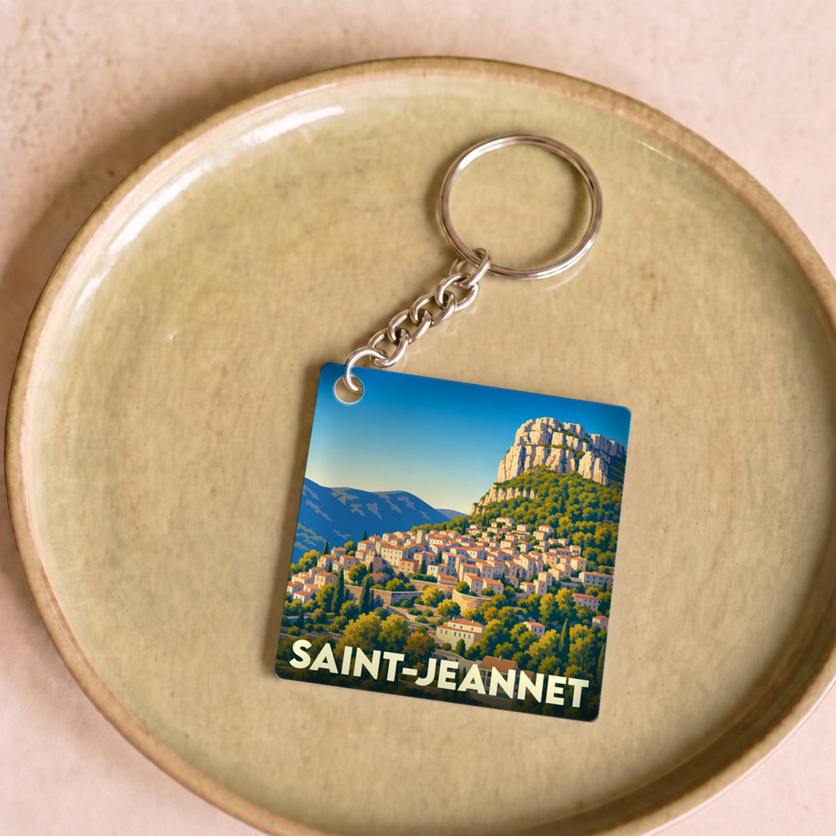 Porte-clés souvenir de la ville de Saint-Jeannet avec une illustration stylisée du village et de son célèbre baou.
