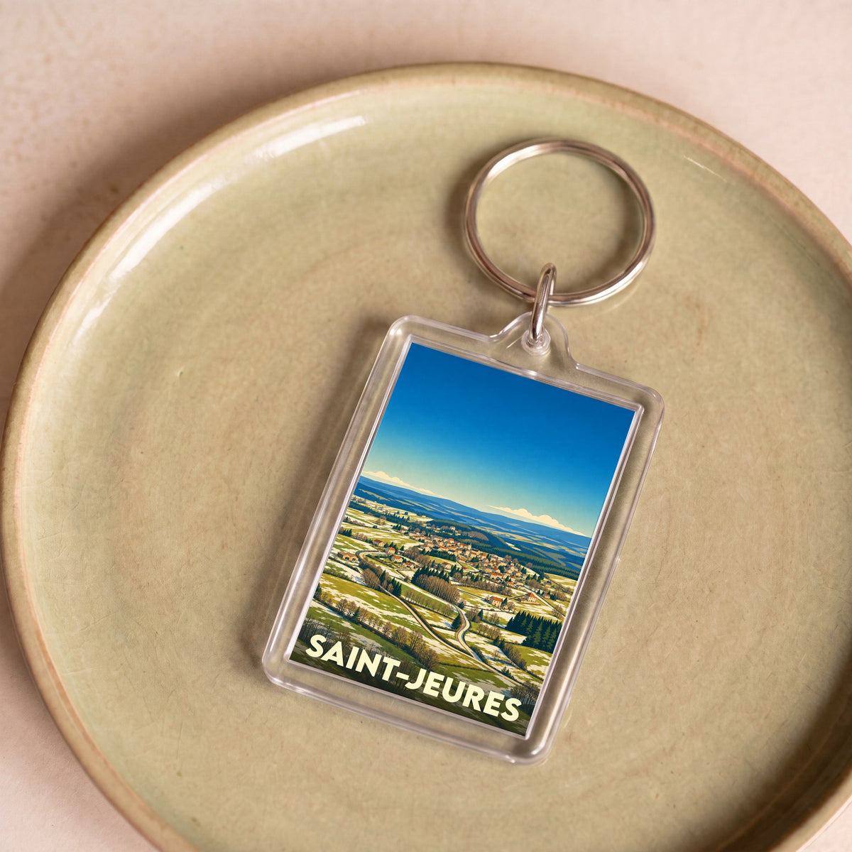 Porte-clés souvenir de la ville de Saint-Jeures avec une illustration panoramique stylisée.