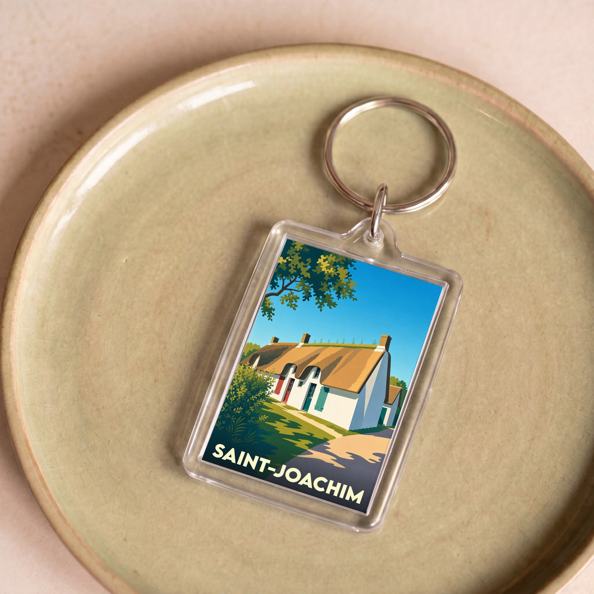 Porte-clés souvenir de la ville de Saint-Joachim avec une illustration stylisée d'une chaumière traditionnelle.