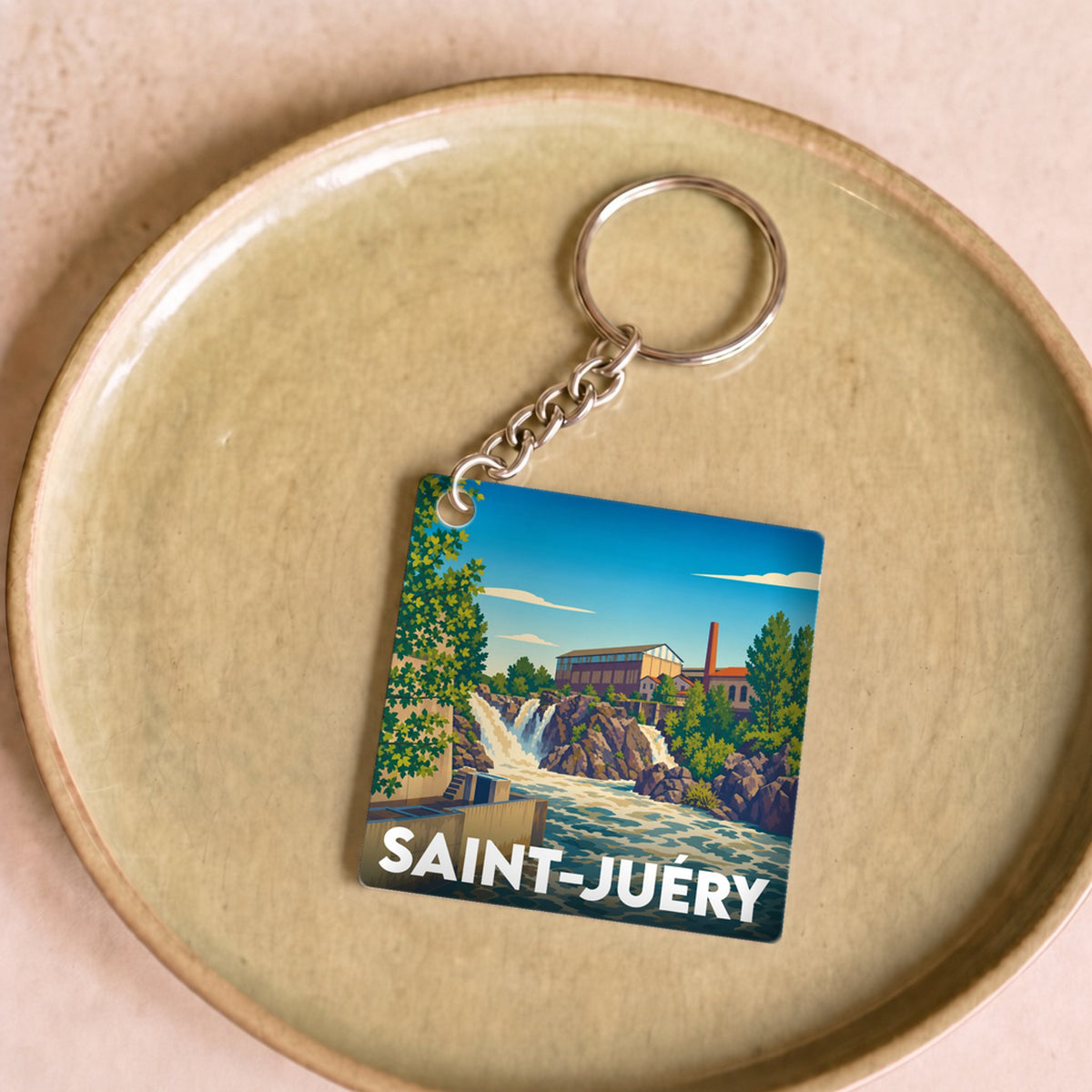 Porte-clés souvenir de la ville de Saint-Juéry avec une illustration stylisée d'un paysage fluvial.