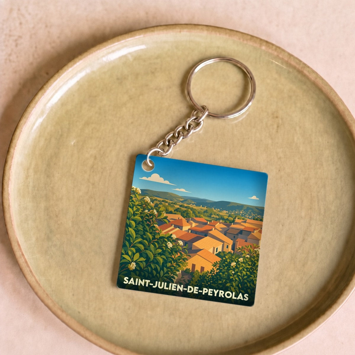 Porte-clés souvenir de la ville de Saint-Julien-de-Peyrolas avec une illustration stylisée.