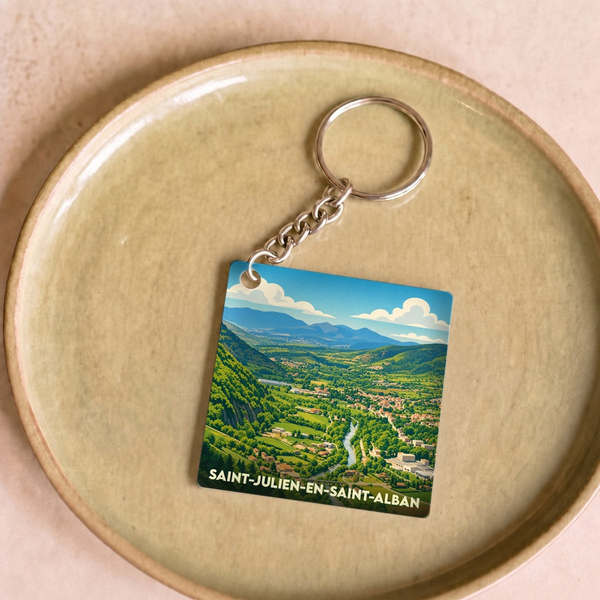 Porte-clés souvenir de la ville de Saint-Julien-en-Saint-Alban avec une illustration stylisée du paysage.
