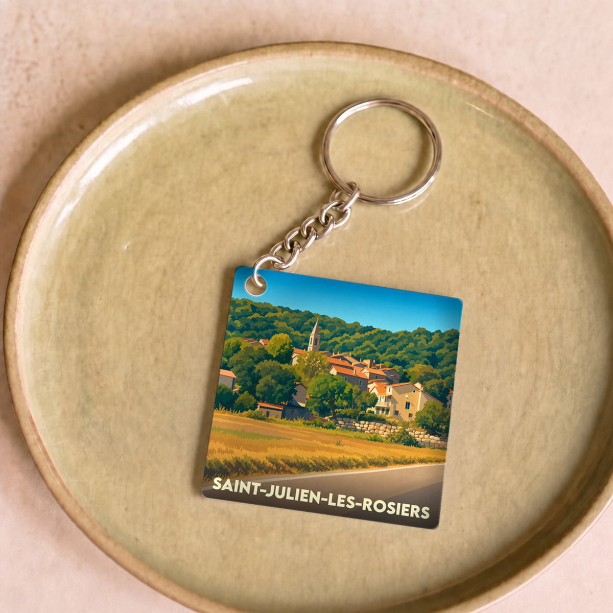 Porte-clés souvenir de Saint-Julien-les-Rosiers avec une illustration stylisée du village et de ses paysages.