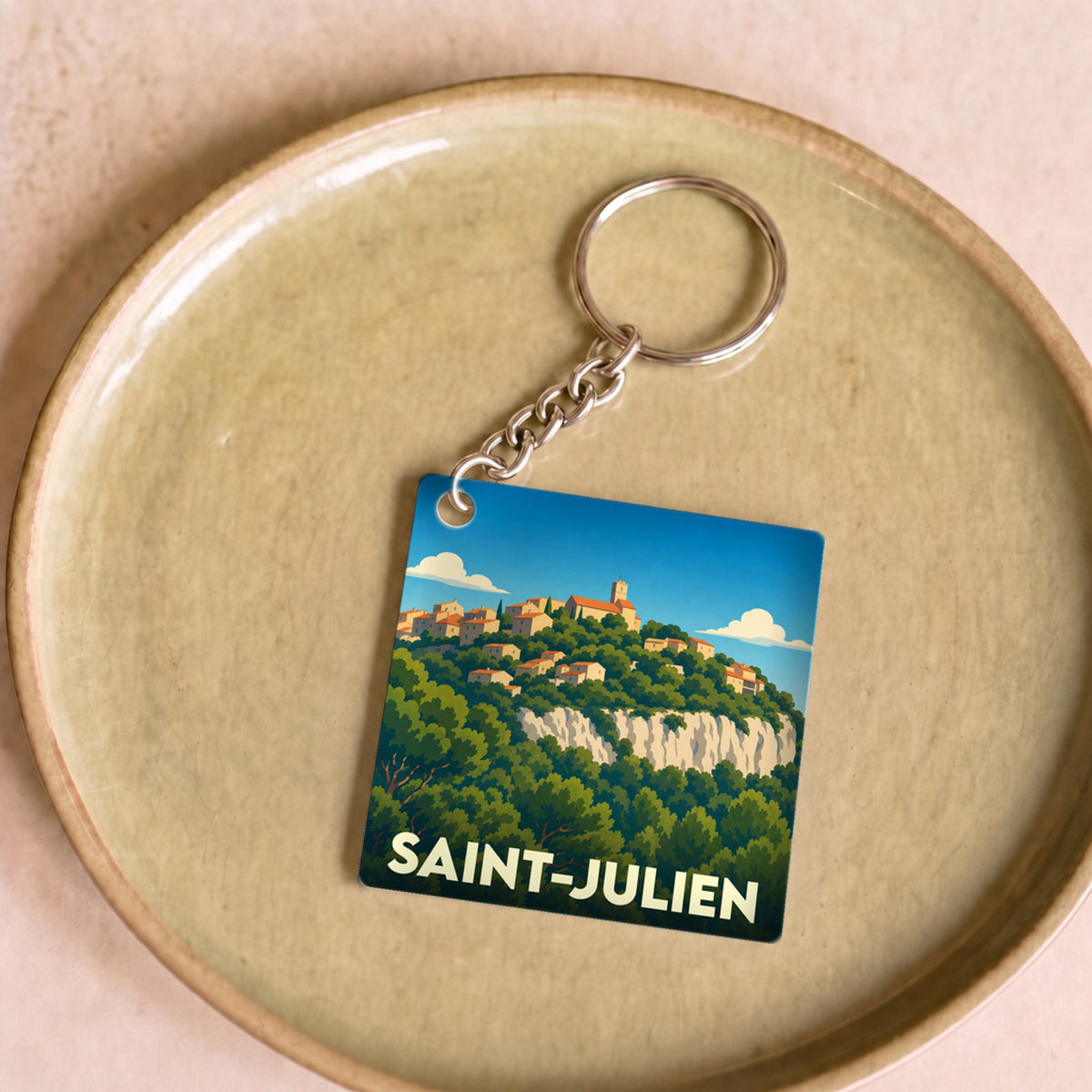 Porte-clés souvenir de la ville de Saint-Julien avec une illustration stylisée d'un village perché.