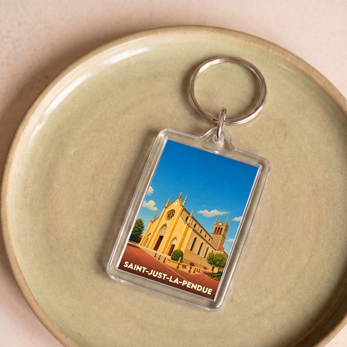 Porte-clés souvenir de la ville de Saint-Just-la-Pendue avec une illustration stylisée de son église.