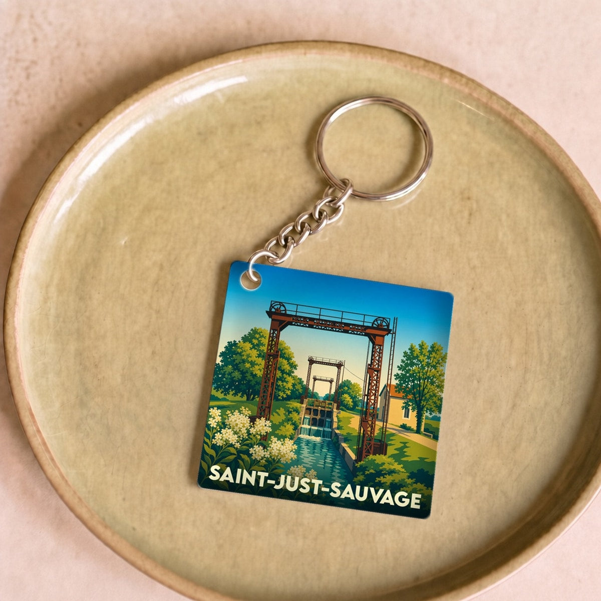 Porte-clés souvenir de la ville de Saint-Just-Sauvage avec une illustration stylisée.