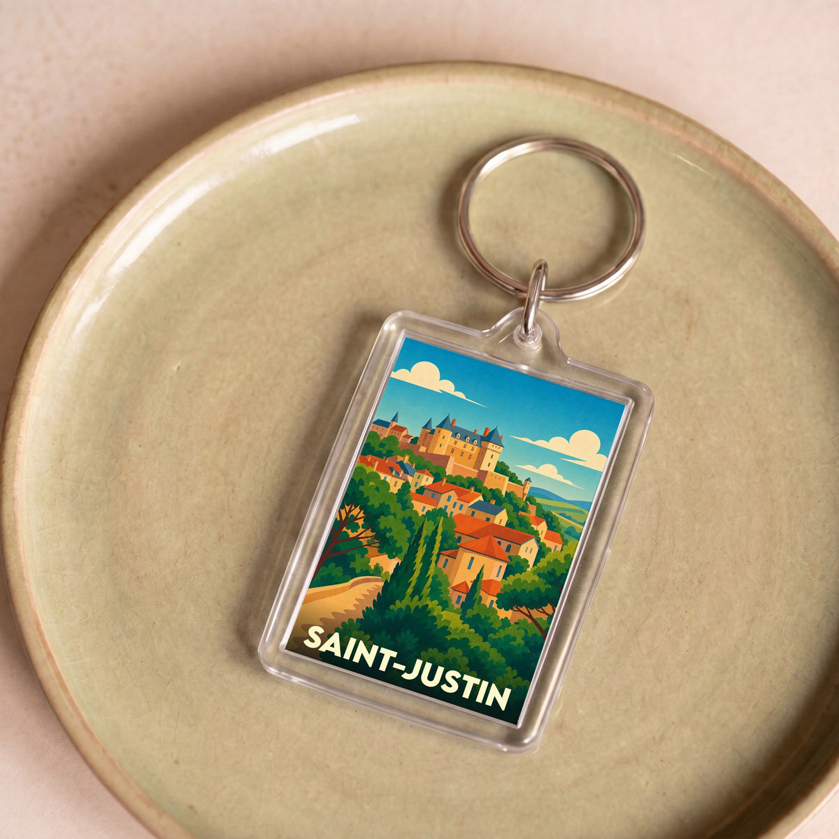 Porte-clés souvenir de la ville de Saint-Justin avec une illustration stylisée d'un village perché.