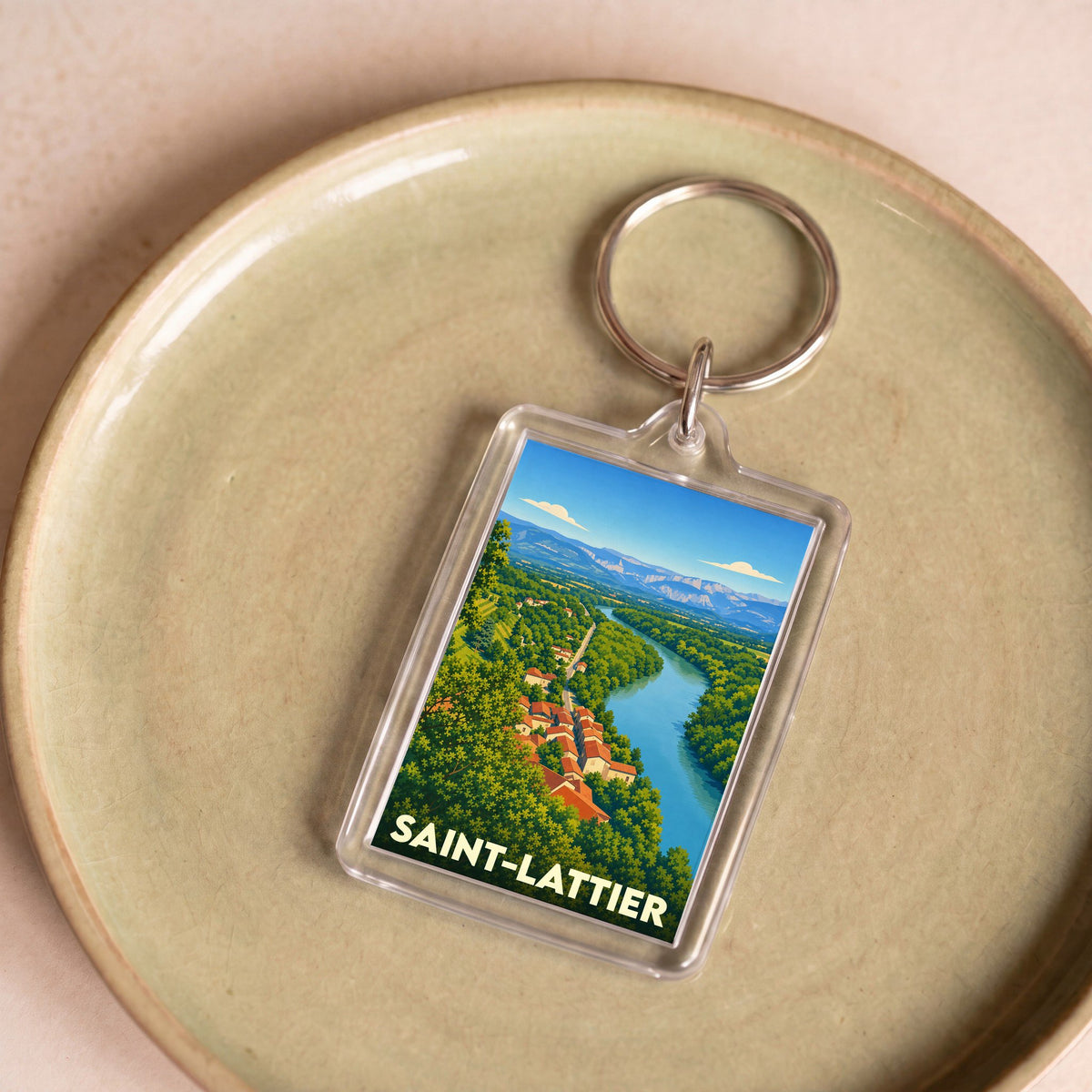 Porte-clés souvenir de la ville de Saint-Lattier avec une illustration stylisée d'un paysage de rivière et de montagnes.