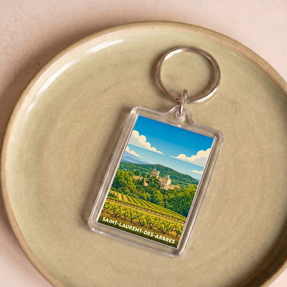 Porte-clés souvenir de la ville de Saint-Laurent-des-Arbres avec une illustration stylisée de son paysage et de ses vignes.