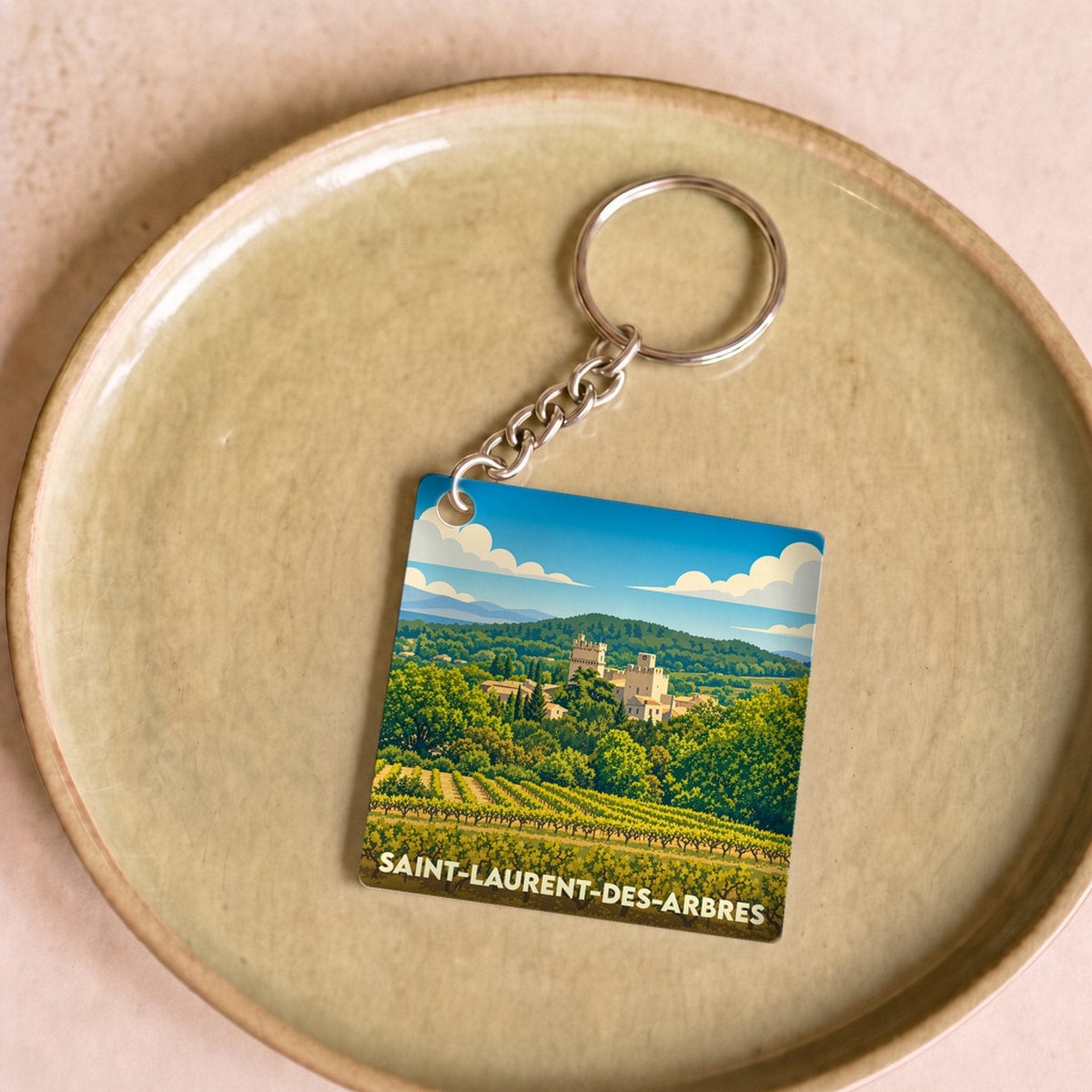 Porte-clés souvenir de la ville de Saint-Laurent-des-Arbres avec une illustration stylisée de son paysage et de ses vignes.
