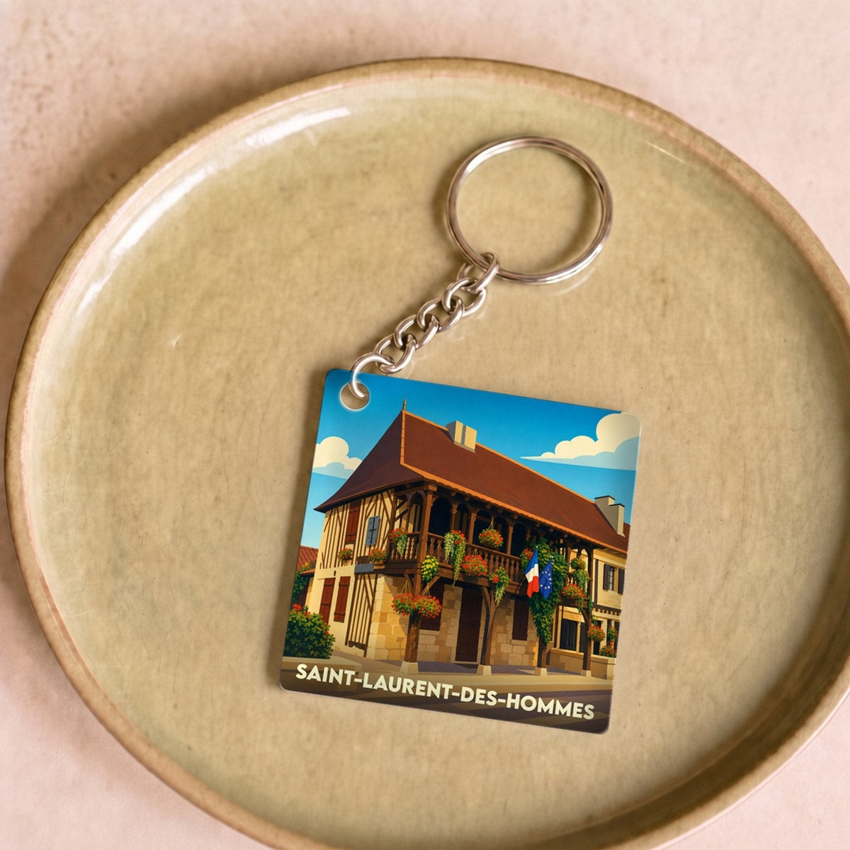 Porte-clés souvenir de la ville de Saint-Laurent-des-Hommes avec une illustration stylisée.