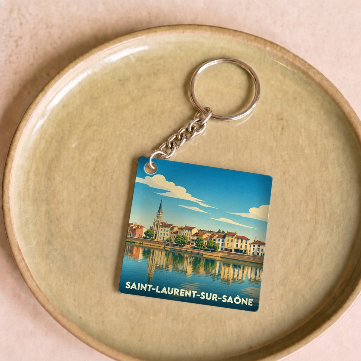 Porte-clés souvenir de la ville de Saint-Laurent-sur-Saône avec une illustration stylisée en bord de rivière.