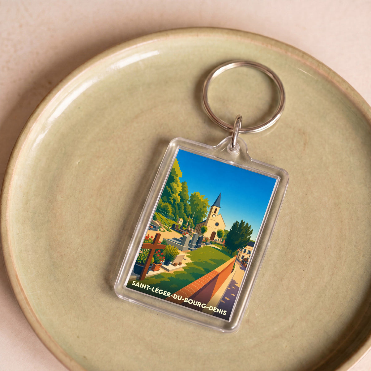 Porte-clés souvenir de la commune de Saint-Léger-du-Bourg-Denis avec une illustration stylisée de son église et son cimetière.