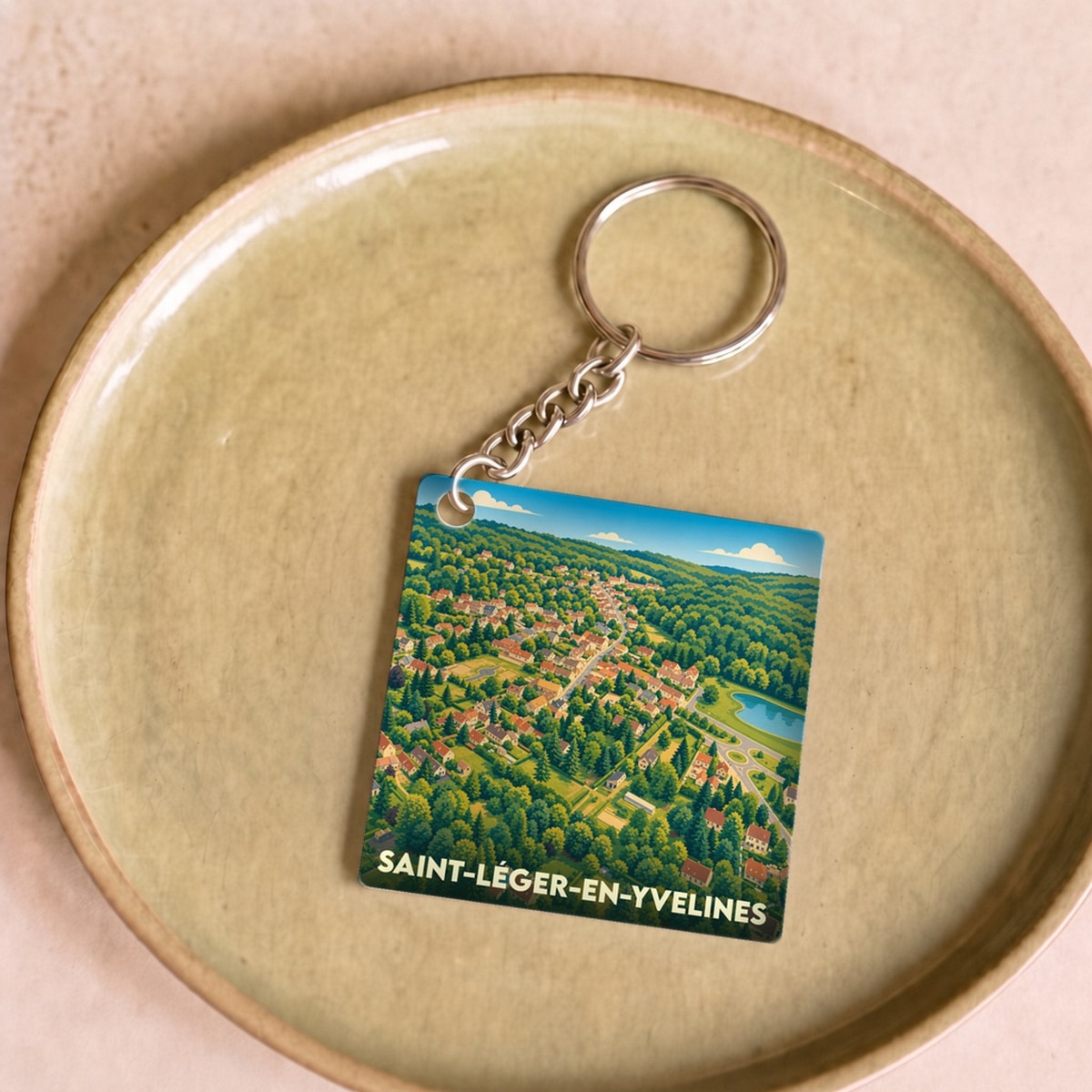 Porte-clés souvenir de la ville de Saint-Léger-en-Yvelines avec une illustration aérienne et stylisée.